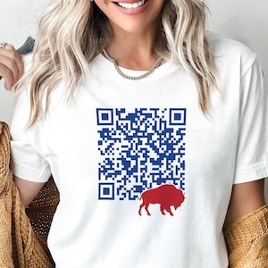 May include: White t-shirt featuring a blue QR code design and a red buffalo silhouette. The shirt is a classic crew neck style, perfect for casual wear. The design is printed on the front of the shirt.