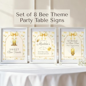 May include: A set of eight party table signs featuring a bee theme with yellow bows, floral patterns, and illustrations of bees. The signs display text including "Sweet Bee Treats," "Welcome to Maddie's 3rd Bee-day Celebration," and "Strike a Bee Pose."