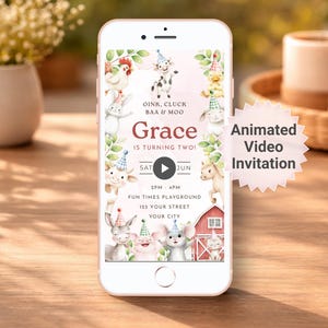 May include: A smartphone displays a birthday invitation with farm animal illustrations. The invitation reads "Grace is turning two!" and includes the text "Animated Video Invitation". The phone is on a wooden surface.