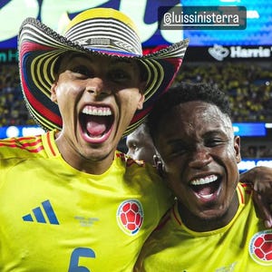 May include: Two individuals wearing yellow soccer jerseys with blue accents and the Colombian national team crest. One person wears a traditional vueltiao hat with black, white, red, and yellow concentric patterns. The text @luissinisterra is visible.