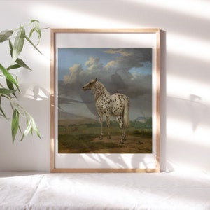 May include: A framed print of a painting depicting a spotted horse standing in a field. The horse is white with black spots and is facing away from the viewer. The background is a landscape with a cloudy sky.
