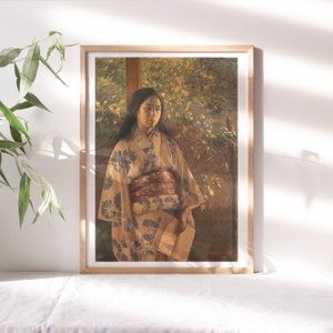 May include: A framed painting of a woman in a traditional Japanese kimono standing in a garden setting. The woman is wearing a light brown kimono with a floral pattern and a dark brown sash. The background is a blurred image of green foliage.