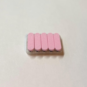 May include: A pink nail file with six rectangular pink pads. The pads are arranged in a row on a clear base. The nail file is designed for smoothing and shaping nails. The background is plain white.