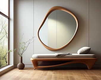 May include: An asymmetrical wooden wall mirror with a smooth, organic frame shape. Below the mirror sits a low wooden bench with a light-colored cushion, a small pillow, and a folded cloth. A dark brown vase with thin branches stands nearby.