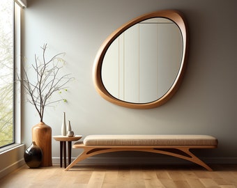 May include: A light wood bench with a beige cushion sits in front of a large, organic-shaped mirror with a wood frame. A vase with branches and two smaller vases are on a small table to the left of the bench.