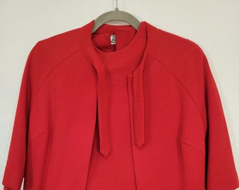May include: A red dress and matching jacket set with a tie detail at the neck. The set is made of a soft, knit fabric.