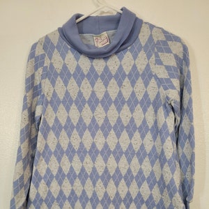 May include: A blue and white argyle patterned turtleneck sweater with a small purple tag that says "Country Miss" on it.