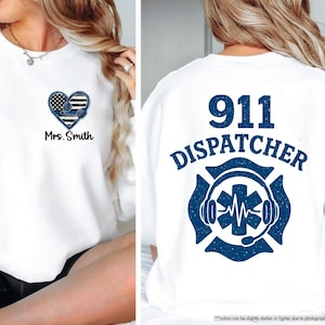 May include: White sweatshirt with a blue and white heart design and the text "Mrs. Smith" on the front. The back of the sweatshirt has a blue and white design with the text "911 DISPATCHER" and a stylized image of a stethoscope and a heart.