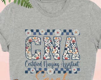 May include: A gray t-shirt with a floral design that says "CNA Certified Nursing Assistant" and the name "Sarah" underneath.