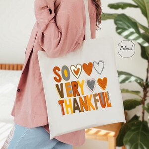 May include: White tote bag with the text "So Very Thankful" in colorful letters and hearts. The bag has a natural fabric label.