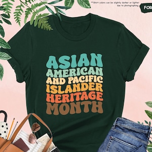 May include: A green t-shirt with the text "ASIAN AMERICAN AND PACIFIC ISLANDER HERITAGE MONTH" in a retro rainbow font.