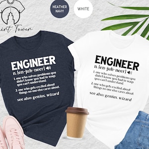 May include: Two t-shirts with a humorous definition of the word "Engineer". The heather navy shirt has white text and the white shirt has black text. Both shirts feature the definition: "n. [en-juh-neer] 1. one who solves problems you didn't know you had in ways you can't understand. 2. one who gets excited about things no one else cares about. see also: genius, wizard"