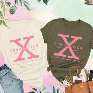 May include: Two t-shirts with a pink "X" graphic and the text "Generation 1965 1980 Raised on Hose Water & Neglect". The shirts are in natural and heather olive colors.