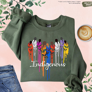 May include: A green sweatshirt with a design of a group of people with feathers and the word "Indigenous" in a dripping paint style.
