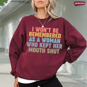 a woman wearing a sweatshirt that says i won't be remembers as a woman