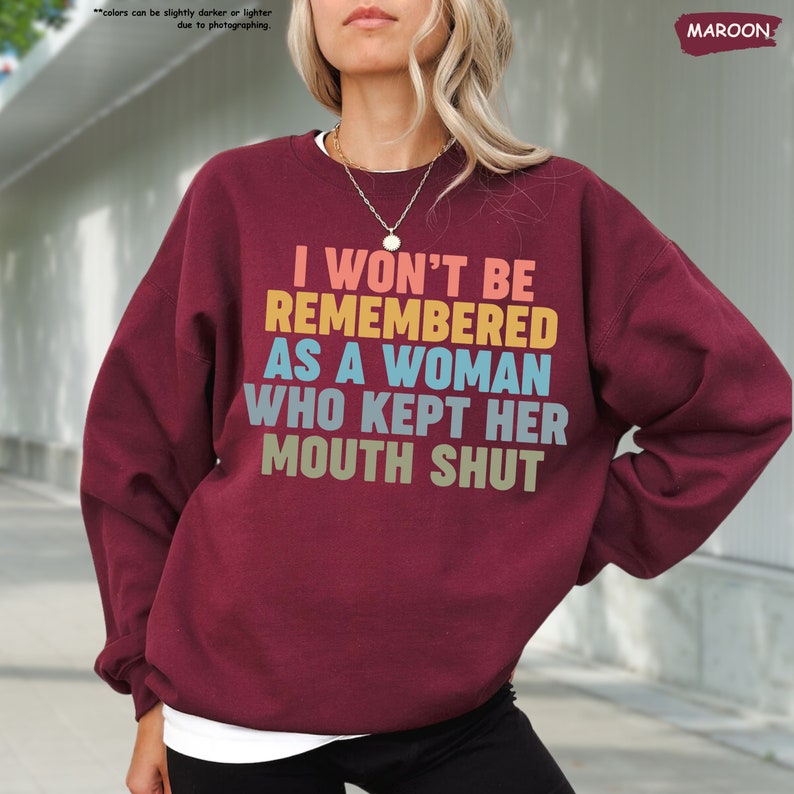 a woman wearing a sweatshirt that says i won't be remembers as a woman