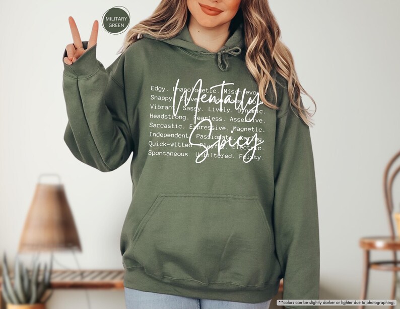 May include: Military green hoodie with a front pocket and a drawstring hood. The hoodie features the words "Mentally Spicy" in a white script font, along with a list of descriptive words. The hoodie is made of a soft material.