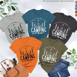 Peut inclure: Cinq t-shirts de diff&eacute;rentes couleurs sur le th&egrave;me du camping. Les t-shirts pr&eacute;sentent un motif de tente, d'arbres, d'une lune et d'&eacute;toiles avec le texte "Fires, Friends, Fun, Camping Crew".