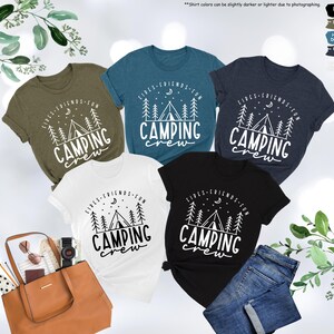 Peut inclure: Cinq t-shirts de diff&eacute;rentes couleurs sur le th&egrave;me du camping. Les t-shirts pr&eacute;sentent un motif blanc d'une tente, d'arbres, d'une lune et d'&eacute;toiles avec le texte "Fires, Friends, Fun, Camping Crew".