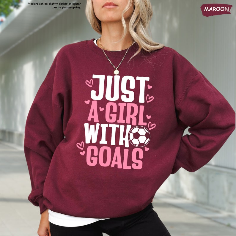 a woman wearing a sweatshirt that says just a girl with goals