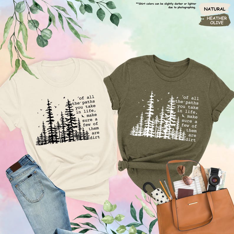 K&ouml;nnte beinhalten: Zwei T-Shirts mit einer Waldszene und dem Text 'of all the paths you take in life, make sure a few of them are dirt'. Das Shirt auf der linken Seite ist hellbeige und das Shirt auf der rechten Seite ist dunkelgr&uuml;n.