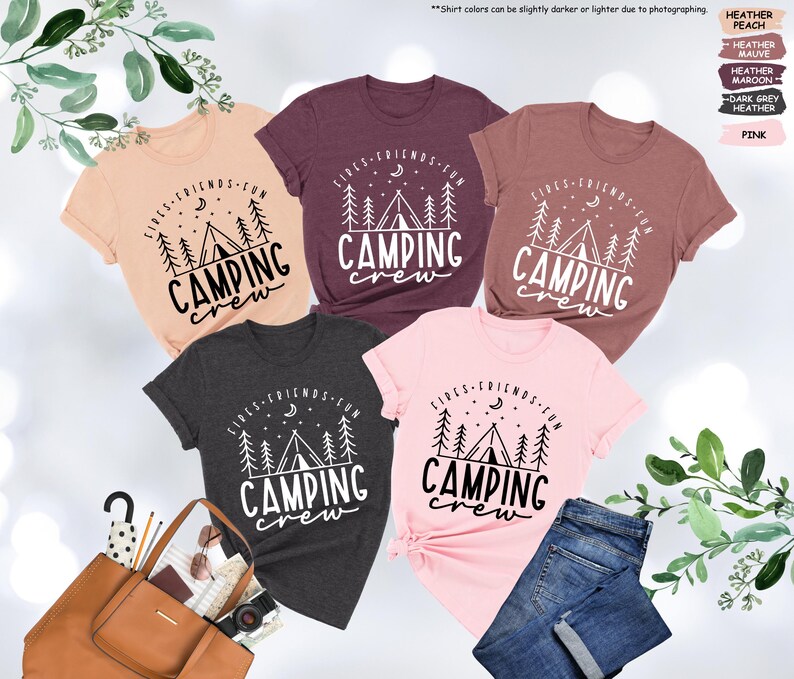 Peut inclure: Cinq t-shirts de diff&eacute;rentes couleurs sur le th&egrave;me du camping. Les t-shirts pr&eacute;sentent un motif blanc d'une tente, d'arbres et d'un croissant de lune avec le texte "Girls - Friends - Fun Camping Crew".
