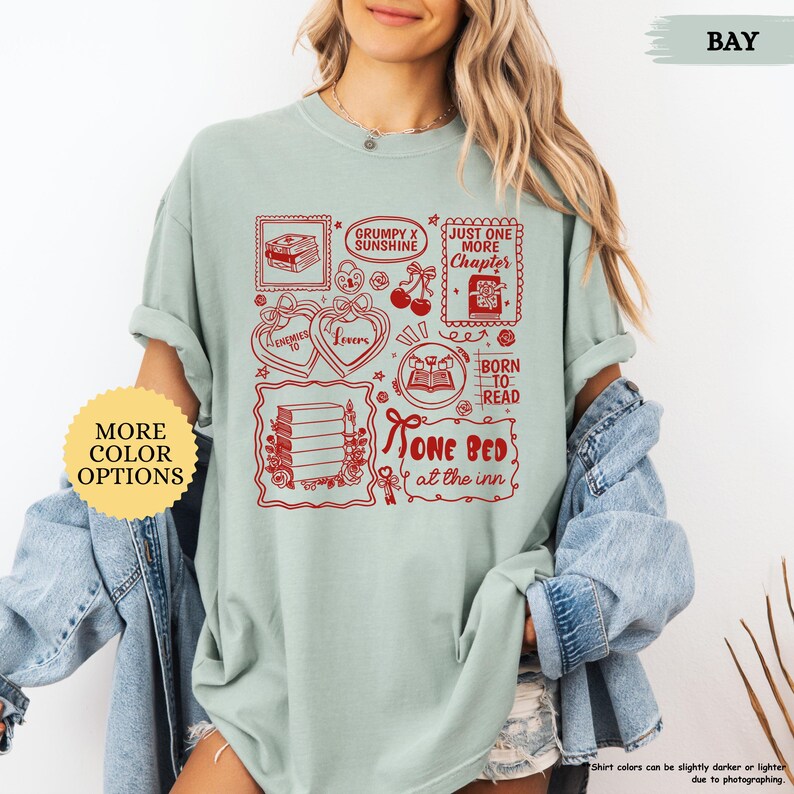 May include: A light green t-shirt with a red graphic design featuring book-themed illustrations and text. The design includes the phrases "Grumpy x Sunshine", "Just One More Chapter", and "One Bed at the Inn".
