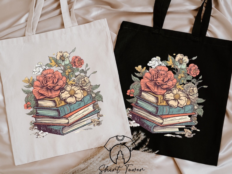 May include: Two tote bags featuring a floral design with a stack of books and flowers. The bag on the left is beige and the bag on the right is black.