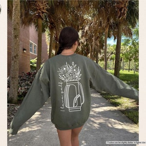 a woman walking down a sidewalk with her arms outstretched