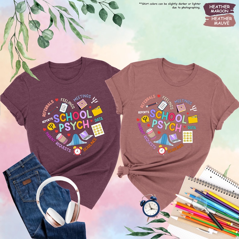 May include: Two heather maroon t-shirts featuring a colourful graphic design that says "School Psych" surrounded by icons representing the work of a school psychologist. The icons include a calendar, a folder, a coffee cup, a laptop, a bell, a pencil, a heart, a brain, and a data file.