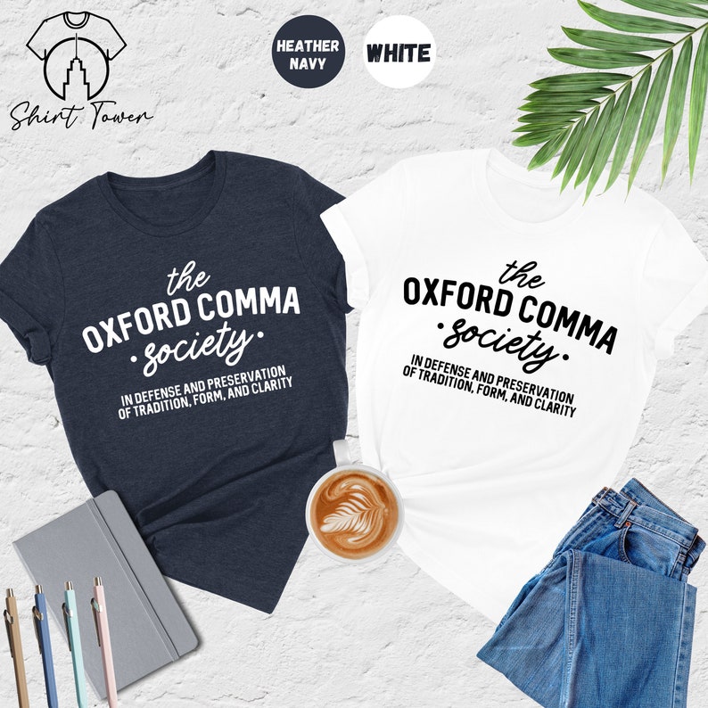 Op de afbeelding: Twee T-shirts met de tekst "the OXFORD COMMA society." in witte letters op een donkerblauw en wit T-shirt. De tekst eronder luidt "IN DEFENSE AND PRESERVATION OF TRADITION, FORM, AND CLARITY".