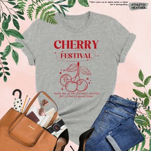 a t - shirt that says cherry festival next to a purse