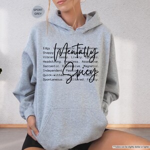 May include: Sport grey hoodie with the words "Mentally Spicy" in a black script font. The hoodie has a drawstring hood and a front pocket. The text is surrounded by a list of adjectives.