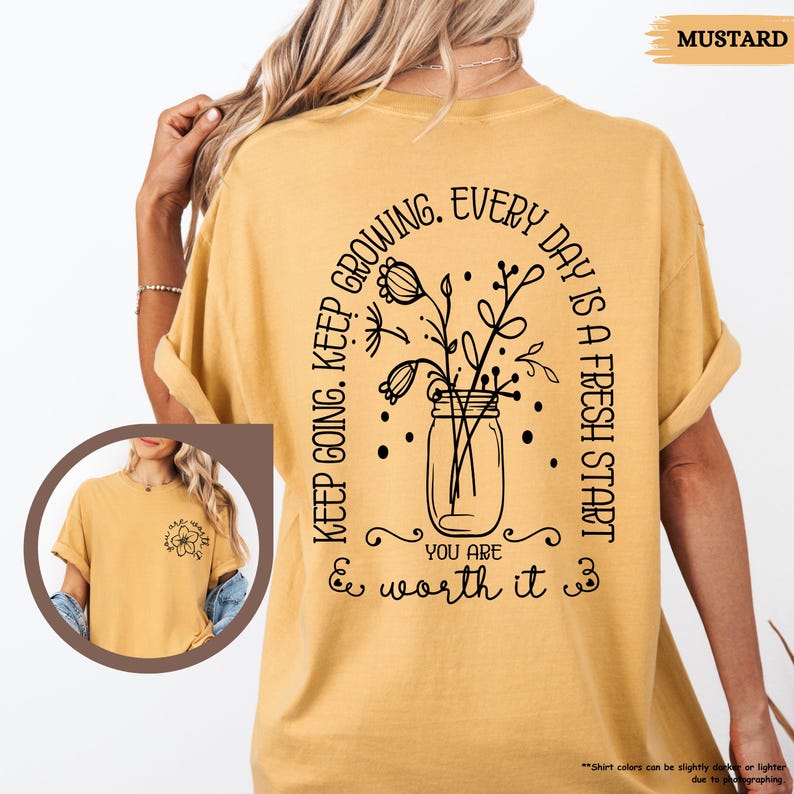 May include: Mustard yellow t-shirt with a black graphic of a jar with flowers and the text "KEEP GOING. KEEP GROWING. EVERY DAY IS A FRESH START YOU ARE & worth it &"