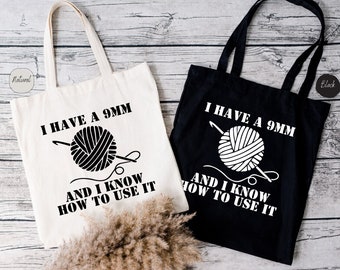 May include: Two tote bags with the text "I have a 9mm and I know how to use it" and a graphic of a ball of yarn and knitting needles. One bag is white and the other is black.