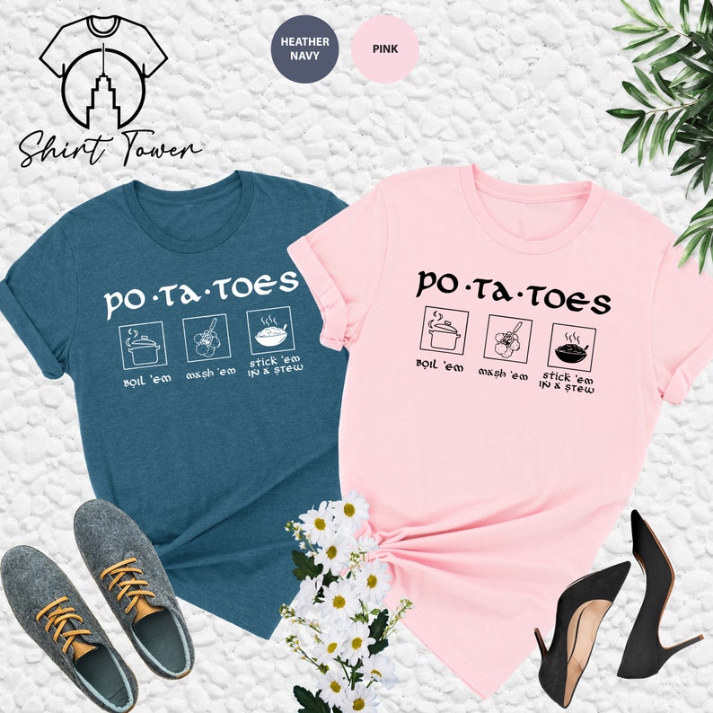May include: Two t-shirts with the text "PO-TA-TOEs" and a graphic of a pot, a flower, and a bowl. The text below the graphic says "Boil 'em mash 'em stick 'em in a stew". One shirt is heather navy blue and the other is pink.