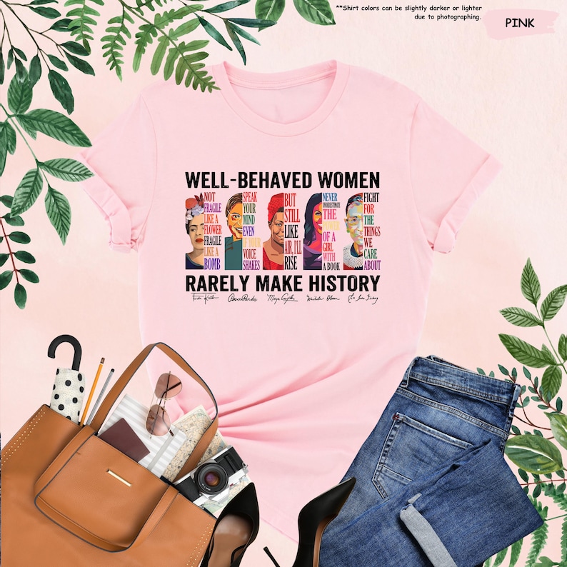 May include: Pink t-shirt with a graphic print of famous women and the text "Well-Behaved Women Rarely Make History". The graphic includes portraits of Frida Kahlo,  Audre Lorde, Maya Angelou, Ruth Bader Ginsburg, and  RBG's quote "Fight for the things that you care about."