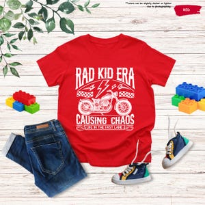 May include: Red t-shirt with a white graphic of a motorcycle and the text "Rad Kid Era Causing Chaos Life in the Fast Lane".