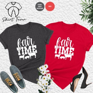 May include: Two t-shirts with the text "fair time" and a graphic of farm animals. The shirts are in dark grey heather and red.