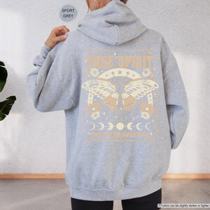 a woman wearing a gray sweatshirt with a graphic on it
