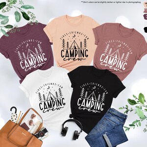 Peut inclure: Cinq t-shirts sur le th&egrave;me du camping. Les t-shirts sont de diff&eacute;rentes couleurs, notamment noir, blanc, p&ecirc;che, marron et mauve chin&eacute;. Chaque t-shirt pr&eacute;sente un motif de feu de camp, de tente et d'arbres avec le texte "Fires, Friends, Fun, Camping Crew".