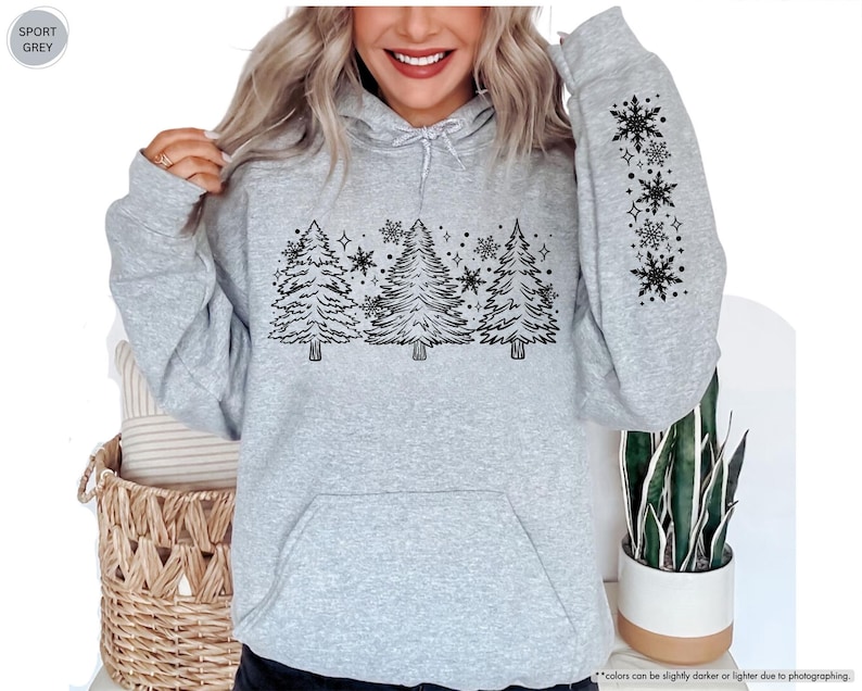 May include: A gray hooded sweatshirt with a black design of stylized pine trees and snowflakes. The design is on the front of the sweatshirt and the sleeve. The text "SPORT GREY" is in a white box on the top left corner of the image.