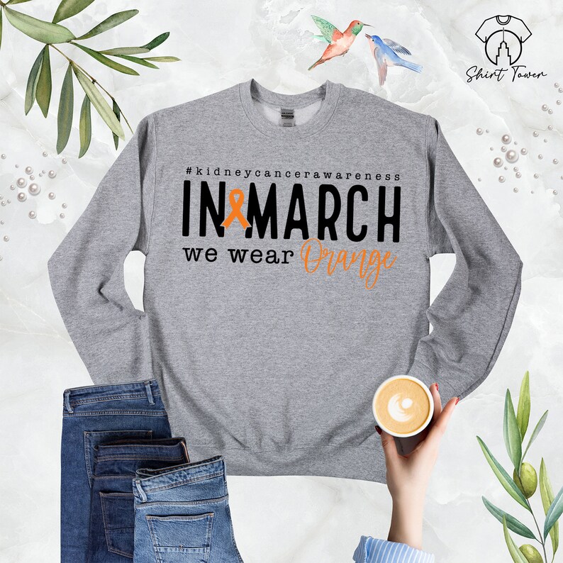 Puede incluir: Sudadera gris con el texto "#kidneycancerawareness IN MARCH we wear Orange" y una cinta naranja.