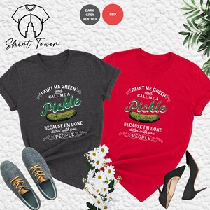 May include: Two t-shirts with a pickle graphic and the text "Paint me green and call me a pickle because I'm done dillin' with you people". One shirt is dark heather grey and the other is red.