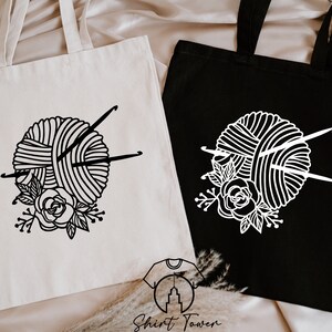 Pu&ograve; includere: Due borse tote con un designo in bianco e nero di un gomitolo di lana con ferri da maglia e un design floreale. La borsa a sinistra &egrave; bianca con un designo nero. La borsa a destra &egrave; nera con un designo bianco.