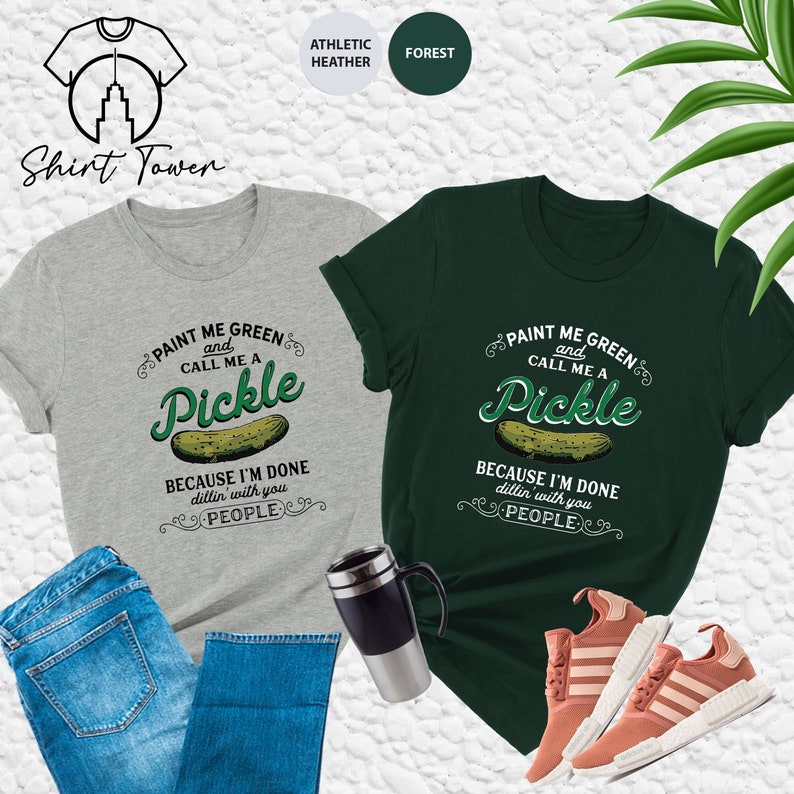 May include: Two t-shirts with a pickle graphic and the text "Paint me green and call me a pickle because I'm done dillin' with you people". The shirts are in athletic heather grey and forest green.