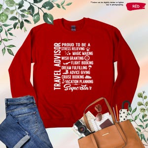 May include: Red long-sleeve shirt with white text that reads "Travel Advisor Proud to be a Stress Relieving Magic Making Wish Granting Flight Booking Dream Fulfilling Advice Giving Cruise Booking Vacation Planning Superstar".