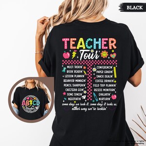 May include: Black t-shirt with a colorful graphic that says "Teacher Tour" and lists tasks teachers do, such as "Multi Tasking", "Book Readin", "Lesson Plannin", "Conferencing", "Paper Gradin", "Snack Dealin", "Coffee Drinkin", "Field Trip Plannin", "Recess Monitorin", "Evaluatin", "Nurturin". The graphic also includes a colorful ABC block design with the text "Teacher Tour".