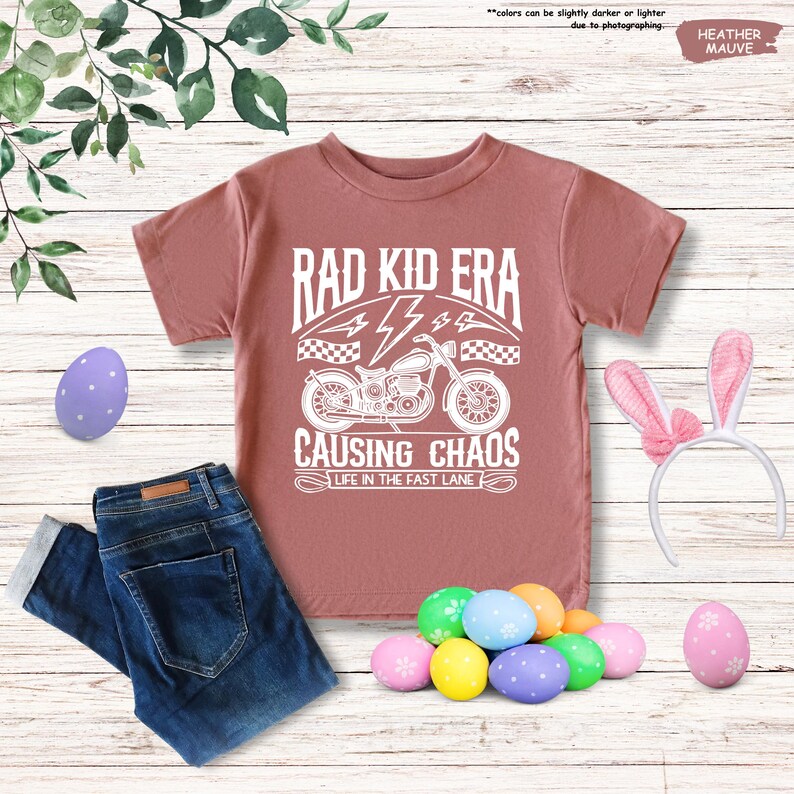 May include: A heather mauve t-shirt with a white graphic of a motorcycle and the text "Rad Kid Era", "4", "Causing Chaos", and "Life in the Fast Lane".
