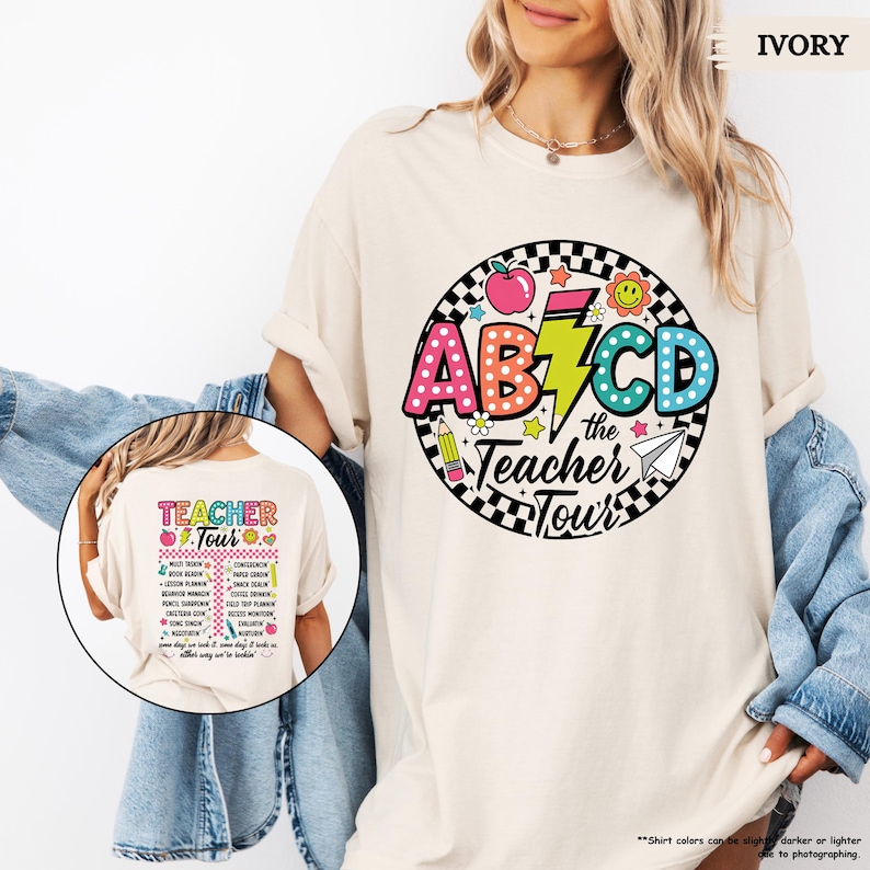 May include: A white t-shirt with a colorful graphic design featuring the letters ABCD, a lightning bolt, and the text "the Teacher Tour".